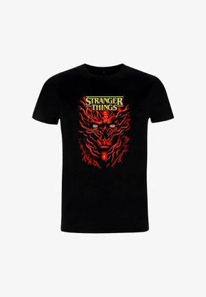 T-shirt nera di cotone con una grafica vivace in rosso e giallo di un volto stilizzato, centrata, con la scritta "STRANGER THINGS" sopra.