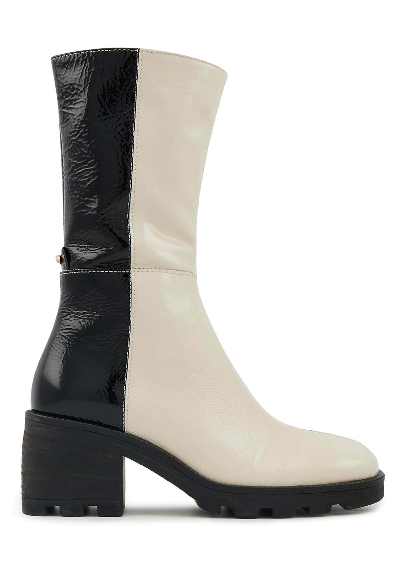 Botte à genoux bicolore en cuir brillant noir et crème, dotée d'un talon carré et d'une semelle en caoutchouc texturé pour une meilleure adhérence.