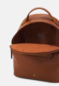 Sac à dos en simili cuir marron avec une poignée sur le dessus, fermeture éclair et des détails cousus. Intérieur doublé avec une étiquette de marque.