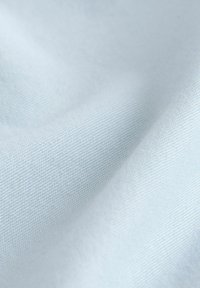 Tissu bleu clair avec une texture lisse et un tissage fin, affichant des variations subtiles de teinte sur toute la surface.
