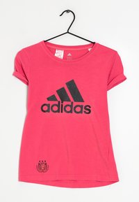 Rosa bomullströja med korta uppvikta ärmar, som har en stor svart 'adidas'-logotyp och en liten skölddesign nära nederkanten. Hänger från en krok.