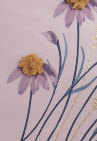 Ein blumenmusterstoff in zartem Rosa zeigt lila Blumen mit goldenen Akzenten und gelben texturierten Blüten, die Tiefe und Kontrast schaffen.