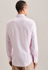 Hemd in hellem Rosa mit spitzem Kragen, Knopfmanschetten und tailliertem Rückendesign. Glatte Textur mit einem dezenten Glanz, maßgeschneiderte Passform.