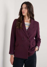 Blazer burdeos de doble botonadura hecho de tejido texturizado. Cuenta con dos bolsillos frontales, botones marrones y un diseño de solapa clásico.