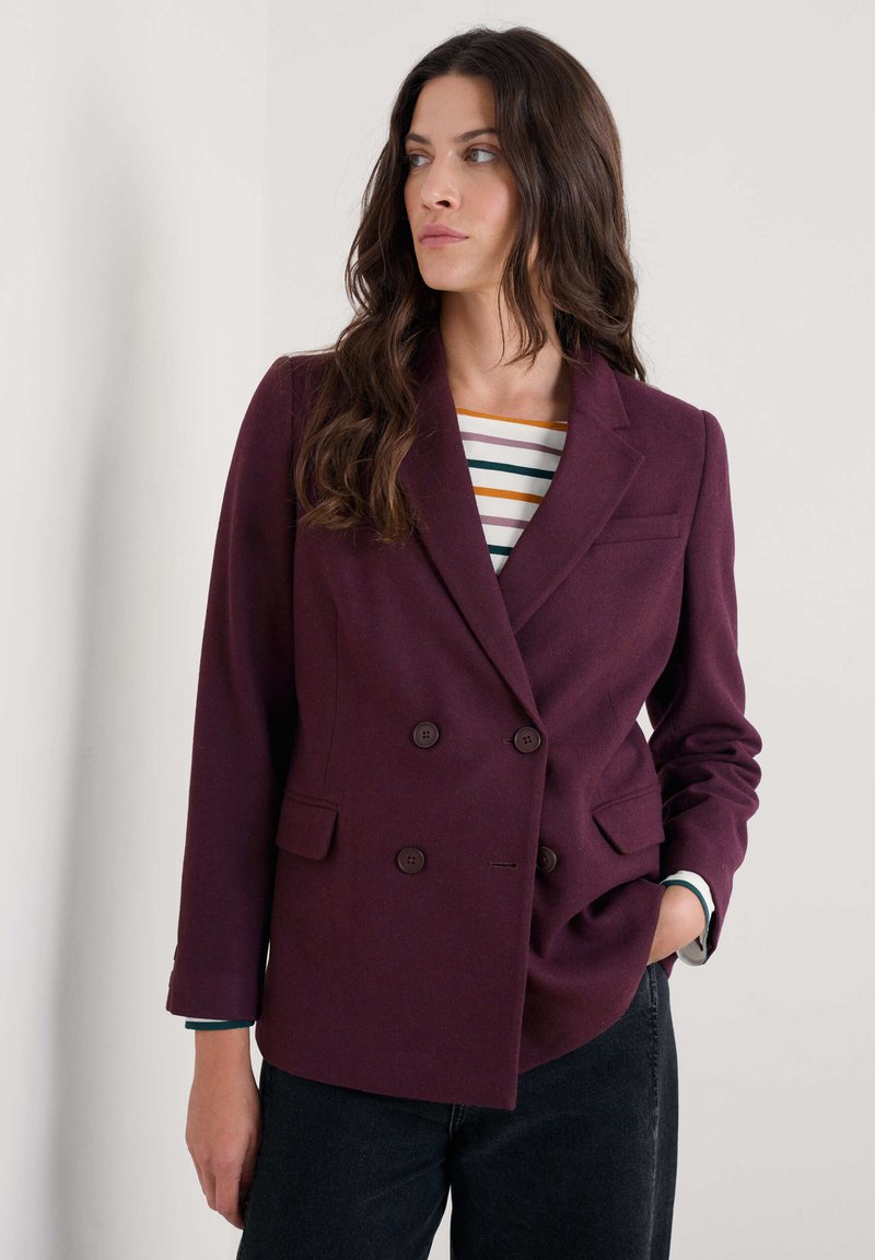 Blazer burdeos de doble botonadura hecho de tejido texturizado. Cuenta con dos bolsillos frontales, botones marrones y un diseño de solapa clásico.