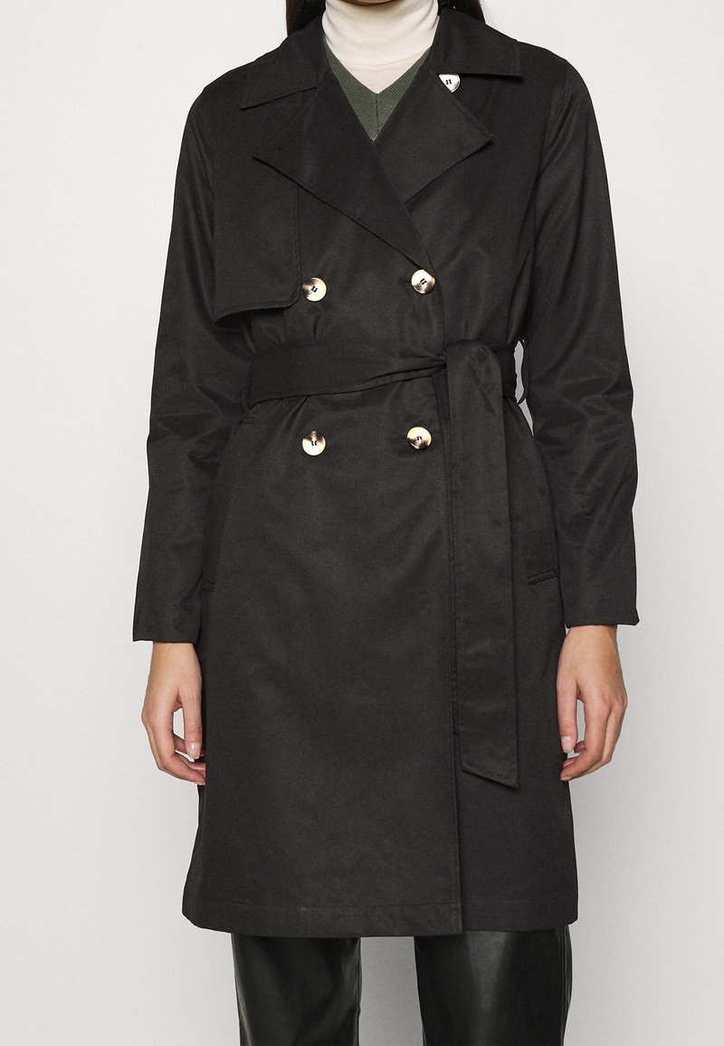Cappotto lungo nero con design doppiopetto, bottoni dorati, vita arricciata e ampi rever. Tessuto liscio e taglio a lunghezza media.
