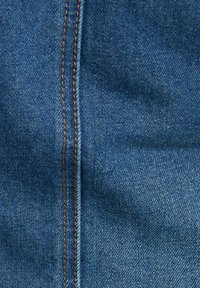 Tissu en denim de bleu moyen avec une surface texturée. Présente une couture centrale bien marquée et des coutures orange contrastées le long des bords.