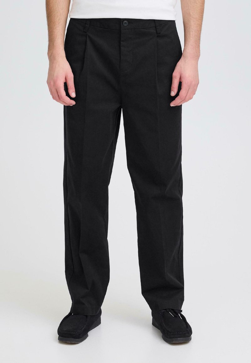 Mustat suorat puuvillahousut, joissa on etutaitteet, nappikiinnitys ja vyölenkit. Yhdistetty mustien loaferien kanssa.