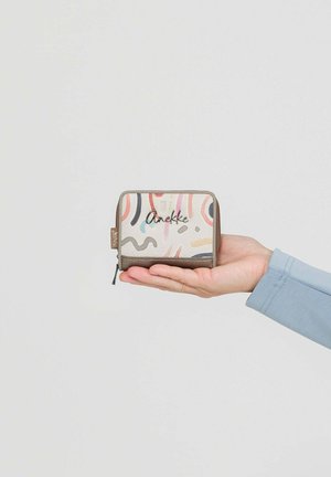 Hand hält eine kleine, mit einem Reißverschluss versehene Brieftasche mit abstrakten Pastellmustern und dem "Anekke"-Logo auf der Vorderseite vor einem schlichten, hellen Hintergrund.