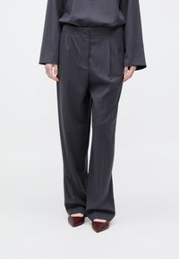 Σκούρο γκρι παντελόνι με πιέτες, κατασκευασμένο από απαλό ύφασμα. Φοριέται με μυτερά μπορντό παπούτσια, που έχουν κομψό σχεδιασμό.