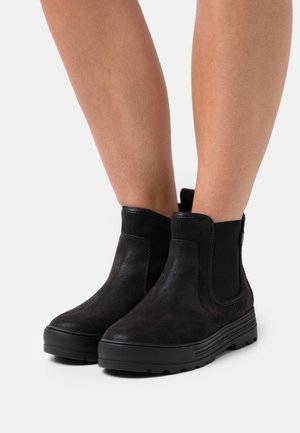 Bottines noires en daim texturé, avec des panneaux latéraux élastiques, un bout rond et une semelle épaisse en caoutchouc avec des rainures profondes.