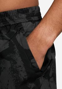 Svarta shorts med en strukturerad, kamouflage-mönster och resårband i midjan. Har en sidficka och ett mjukt tyg.