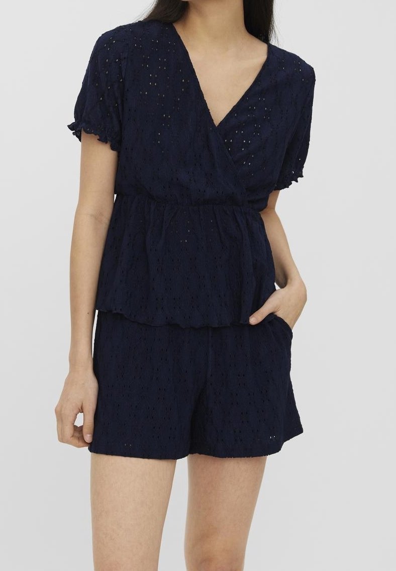 Tmavě modrý krajkový peplum top s krátkými rukávy a výstřihem do V, v kombinaci s odpovídajícími šortkami. Má texturovaný vzor a boční kapsy.