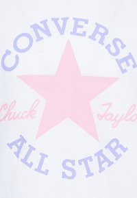 Camisa blanca de algodón con una gran estrella rosa y el texto "CONVERSE", "ALL STAR" y "Chuck Taylor" en colores púrpura y rosa.