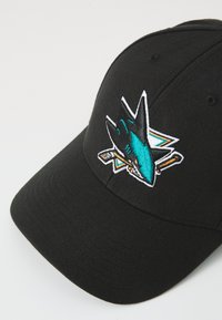 Schwarze Baseballmütze mit gesticktem Haifischlogo in Teal und Weiß, das ein gekreuztes Schlägerdesign zeigt. Strukturierte Form, glatte Textur.
