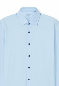 Chemise à manches longues bleu clair en tissu jersey ; elle présente un col classique et sept boutons sombres sur le devant.