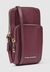 Borsa a tracolla in pelle bordeaux con dettagli in metallo dorato, molteplici tasche con cerniera e una texture liscia. Presenta il logo del marchio sul davanti.