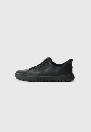 Black sneaker featuring a smooth leather upper, rounded toe, and a textured rubber outsole with a thick design. Laced closure with minimal detailing.