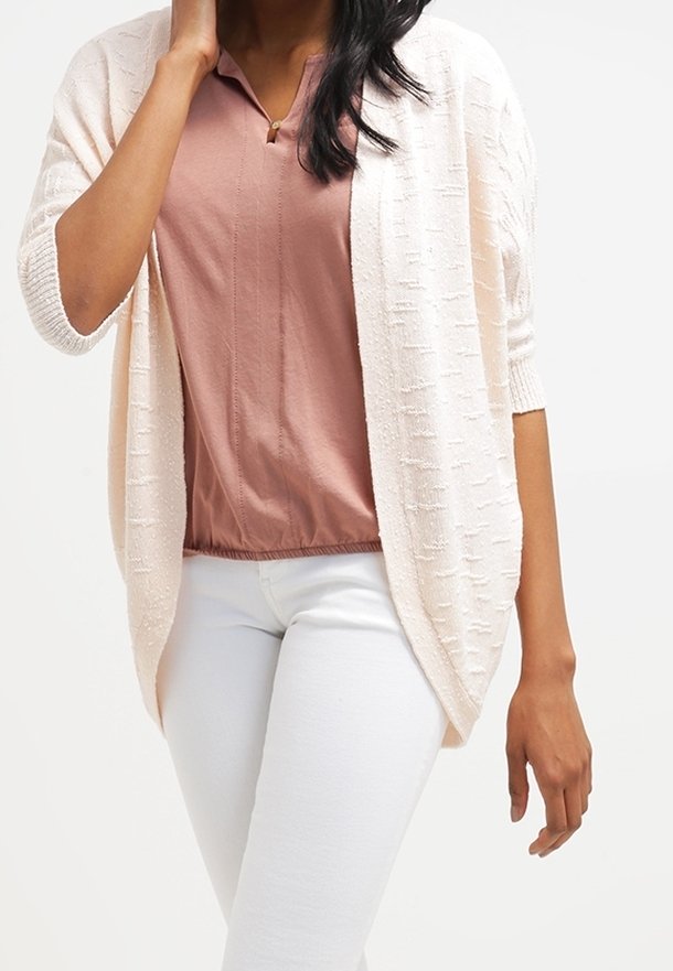 Světle růžový, strukturovaný pletený kardigan s otevřeným předním dílem, tříčtvrtečními rukávy, nošený přes lila blůzu a bílé kalhoty.