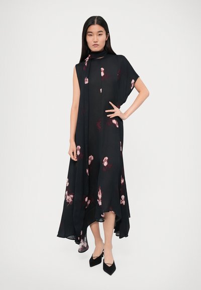 Black chiffon dress with short sleeves, asymmetrical hem, featuring pink floral patterns and a high neckline, paired with black heels.