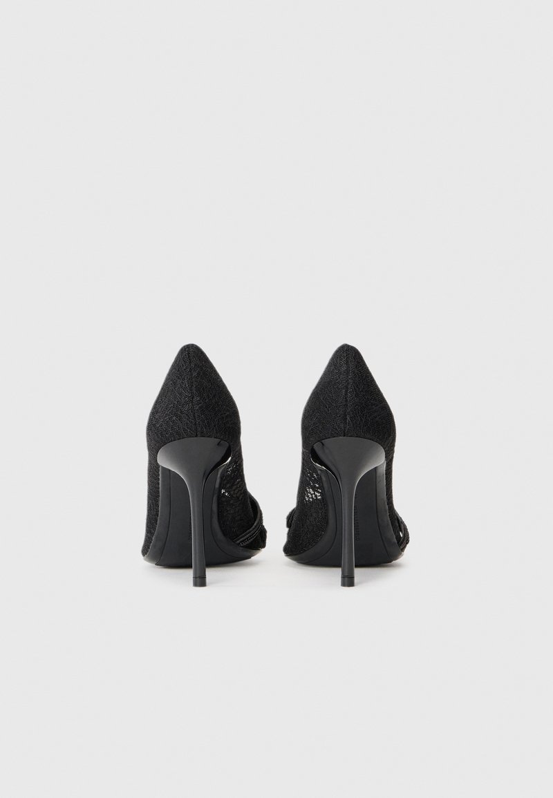 Schwarze High Heels mit strukturiertem Obermaterial, spitzem Zehenbereich und schlankem Stiletto-Absatz. Offene Seiten verleihen ein modernes Designelement.