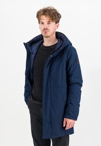 Marineblauwe buitenjack met een gewatteerde, geïsoleerde voering. Beschikt over een capuchon, voorzakken en een moderne snit. Gemaakt van glad, waterdicht materiaal.