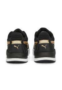 Paire de baskets Puma noires et dorées vues de dos, avec des semelles blanches et le logo Puma sur les contreforts du talon.