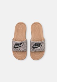 Sandales slides Nike beige avec des sangles noires et blanches à motifs et des semelles intérieures texturées et rembourrées, vues de dessus.