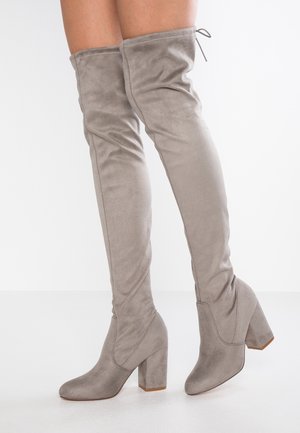 Gray over-the-knee boots made of soft suede with a block heel. Features a fitted shaft and a tie detail at the top.