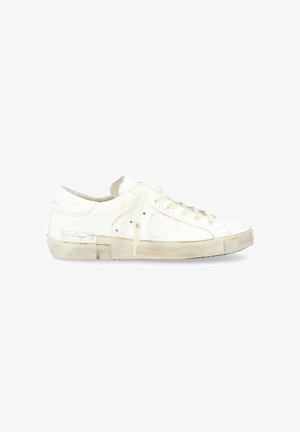 Sneaker bassa bianca con tomaia in pelle liscia, punta rotonda, chiusura con lacci e suola in gomma leggermente consumata, con branding discreto.