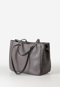 Borsa tote in pelle grigia con lunghe cinghie per la spalla, texture morbida e una forma strutturata ma leggermente floscia su uno sfondo bianco.