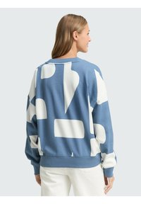 Blauwe sweatshirt met grote witte abstracte vormen, ronde halslijn en een ontspannen pasvorm. Gemaakt van een zachte, gestructureerde stof.