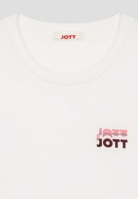 Camiseta de algodón blanca con escote redondo y un logotipo "JOTT" multicolor en el lado izquierdo del pecho, con acentos degradados en rosa y marrón.