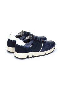 Chaussures bleu marine en cuir et daim, avec un accent de talon blanc et un panneau latéral texturé, dotées d'une semelle en caoutchouc pour une meilleure adhérence.