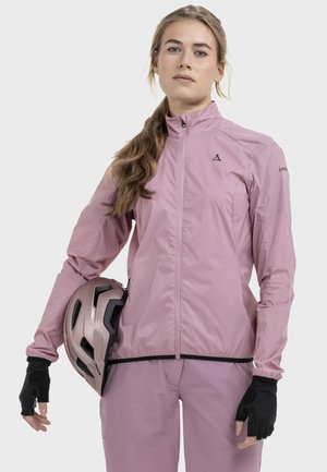 Leichte rosa Fahrradjacke mit hohem Kragen und Reißverschluss, kombiniert mit schwarzen fingerlosen Handschuhen und einem rosa Helm.