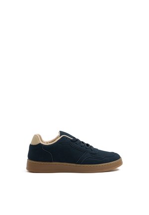 Zapatilla baja azul marino con forro beige, cordones delanteros y suela gruesa de goma marrón, mostrada de perfil sobre fondo blanco.