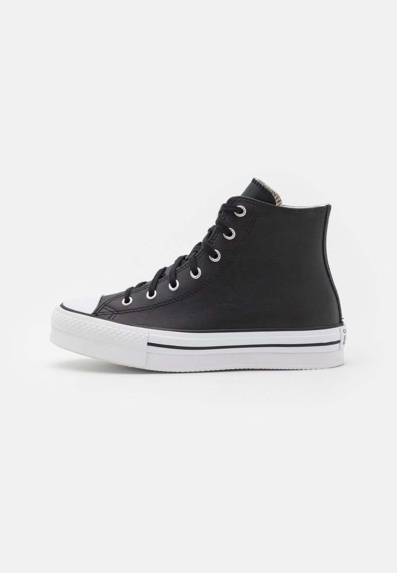 Basket montante noire avec semelle et bout en caoutchouc blanc, lacets noirs et œillets métalliques, vue de profil sur fond blanc.