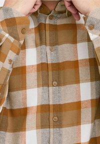 Camisa de cuadros marrón y naranja hecha de una tela texturada, con un cierre de botones en la parte delantera, un cuello y botones visibles a lo largo de la tapeta y los puños.