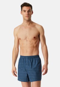 Navyblauwe geruite zwemshorts met een elastische tailleband en een knoop aan de voorkant. Gemaakt van lichtgewicht stof, ideaal voor het zwemmen.