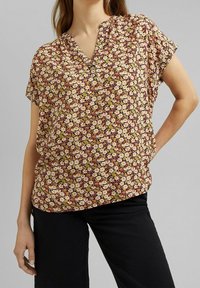 Blusa con motivo floreale, scollatura a V, maniche corte e vestibilità comoda. Presenta fiori rosa, bianchi e verdi su uno sfondo bordeaux.