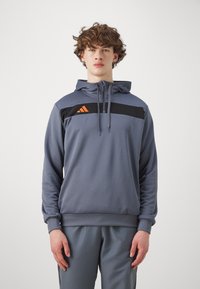 Grauer Hoodie aus weichem Material, mit einem schwarzen horizontalen Streifen und orangefarbenem Logo auf der Brust, mit einer Fronttasche und einer verstellbaren Kapuze.