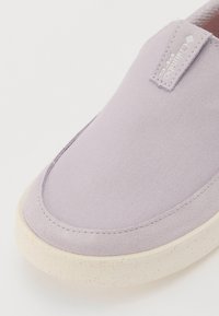 Világos lila slip-on cipő texturált vászon felsőrésszel, puha bőrbetétekkel és pöttyös krém színű talppal. Columbia logó az oldalon.