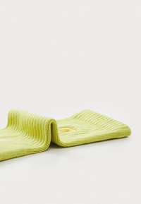Rippige grüne Baumwollsocke mit einem Aufschlag, die in der Mitte einen kleinen gelben Akzent aufweist. Glatte Textur und gleichmäßige Form.