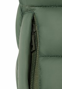 Nahaufnahme eines grünen, gepolsterten Jackenreißverschlusses mit Stoffpolsterung und detaillierter Nahtführung.