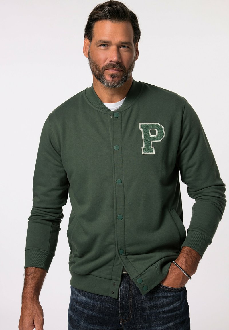 Grön, lätt sweatshirt med rund hals och knäppning, med en texturerad "P"-patch på vänster sida. Ribbstickade mudd och nederkant.