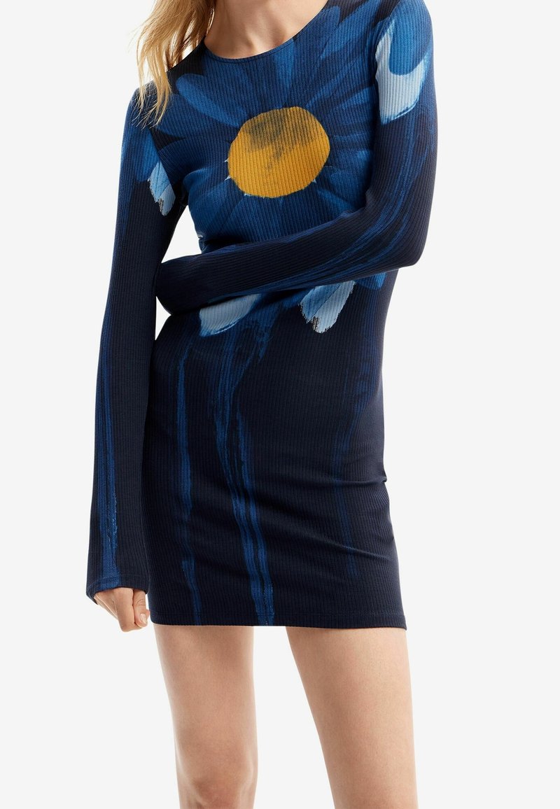 Vestido de manga larga con textura acanalada, fondo azul marino oscuro con patrón floral azul y un centro amarillo, diseño ceñido.