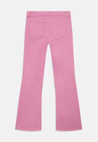 Rosa flagrende jeans med en glatt tekstur, med to baklommer og beltehanker, som viser en jevn farge gjennom hele.