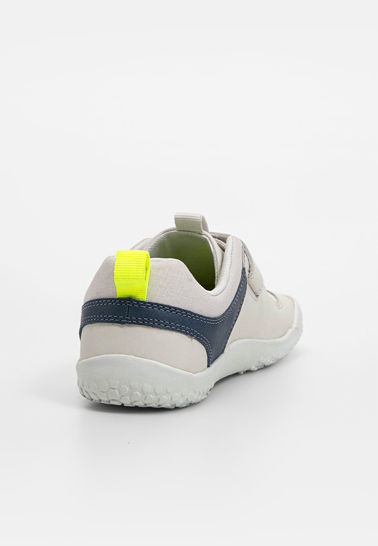 Jasnoszare sneakersy z granatowymi akcentami i jasnosłonecznym uchwytem na pięcie. Teksturowana gumowa podeszwa i konstrukcja typu slip-on dla łatwego zakładania.