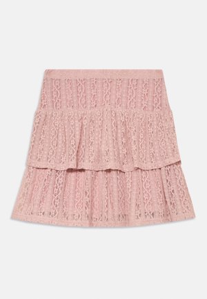 Rozā mežģīņu svārki ar kārtainām volāniem un mežģīņu audumu ar ziedu rakstu, attēloti uz baltas virsmas.