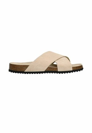 Beige suede cross-strap slide sandal with a cork footbed and black scalloped rubber sole. Minimalistic design with a smooth texture.
